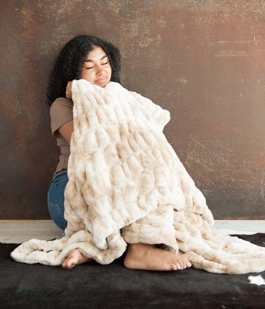 Woman cuddling up in her Cotton Candy Caramel Hugs blanket by Minky Couture.