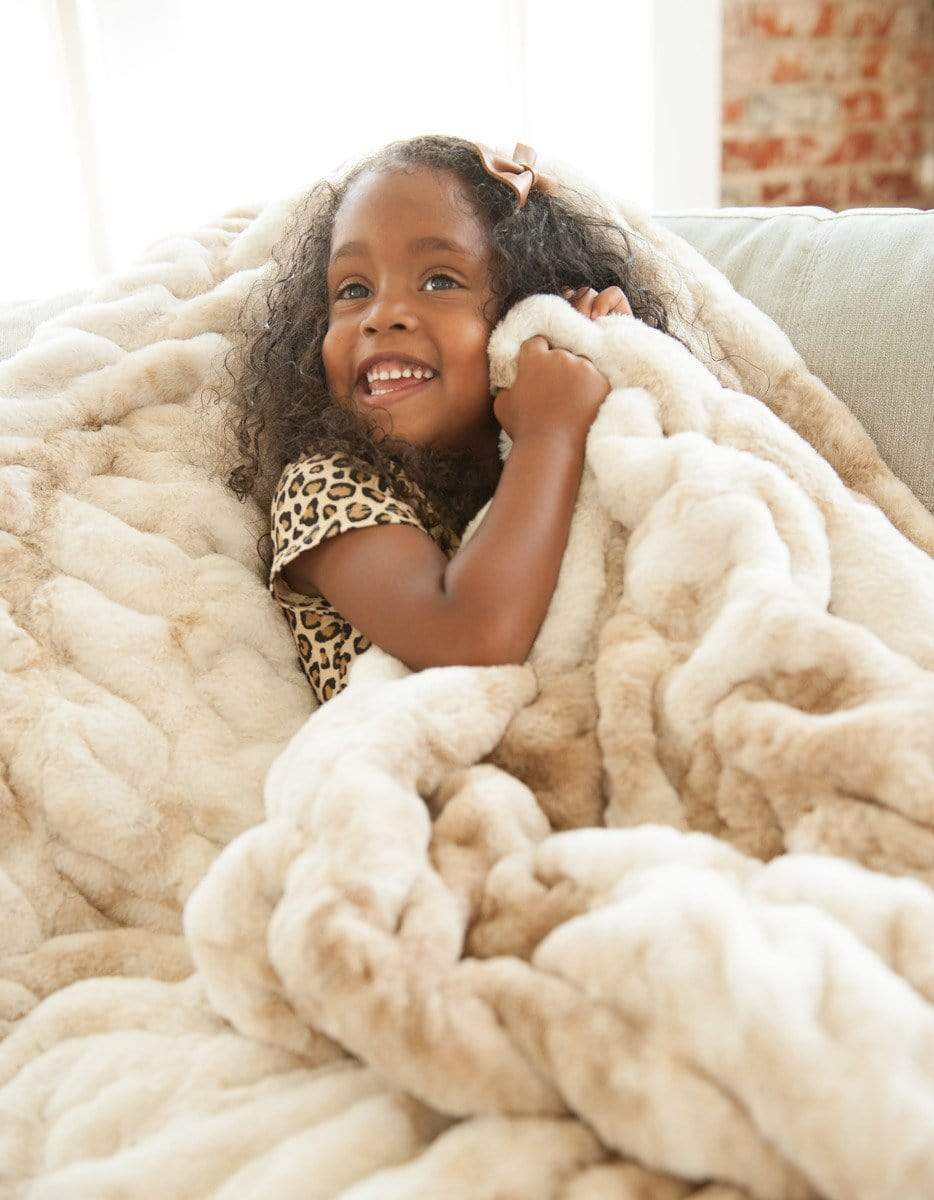 Little girl snuggling up in her plush cotton candy caramel hugs blanket by Minky Couture. 