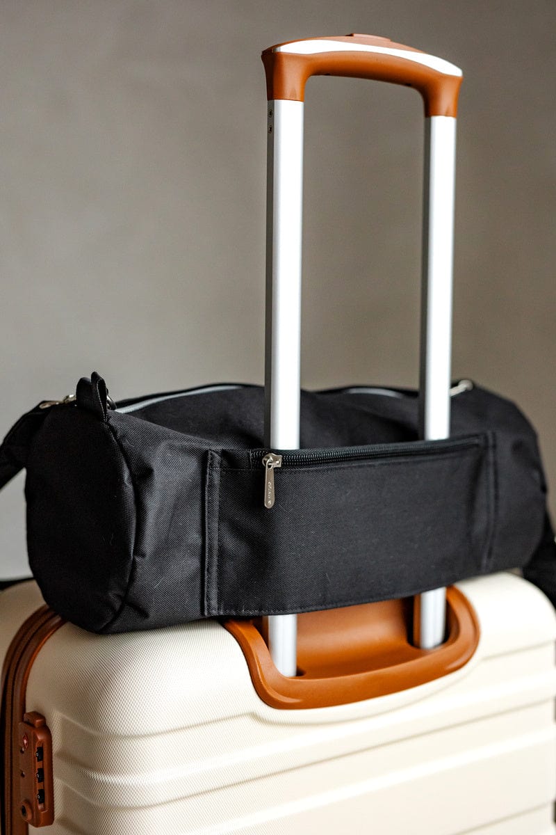 Minky Couture blanket travel bag slung over the handle of cream luggage.