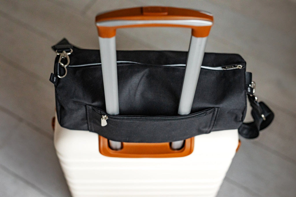 Black Minky Couture blanket travel bag fitted over the handle of a rolling suitcase.