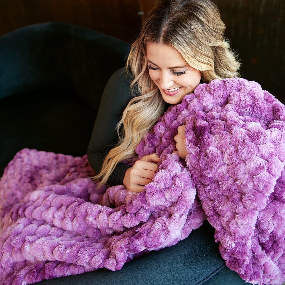 Woman holding a purple waffle textured blanket.