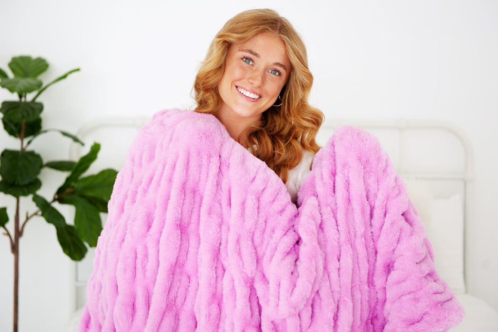 Young woman holding a hot pink ruched blanket. 