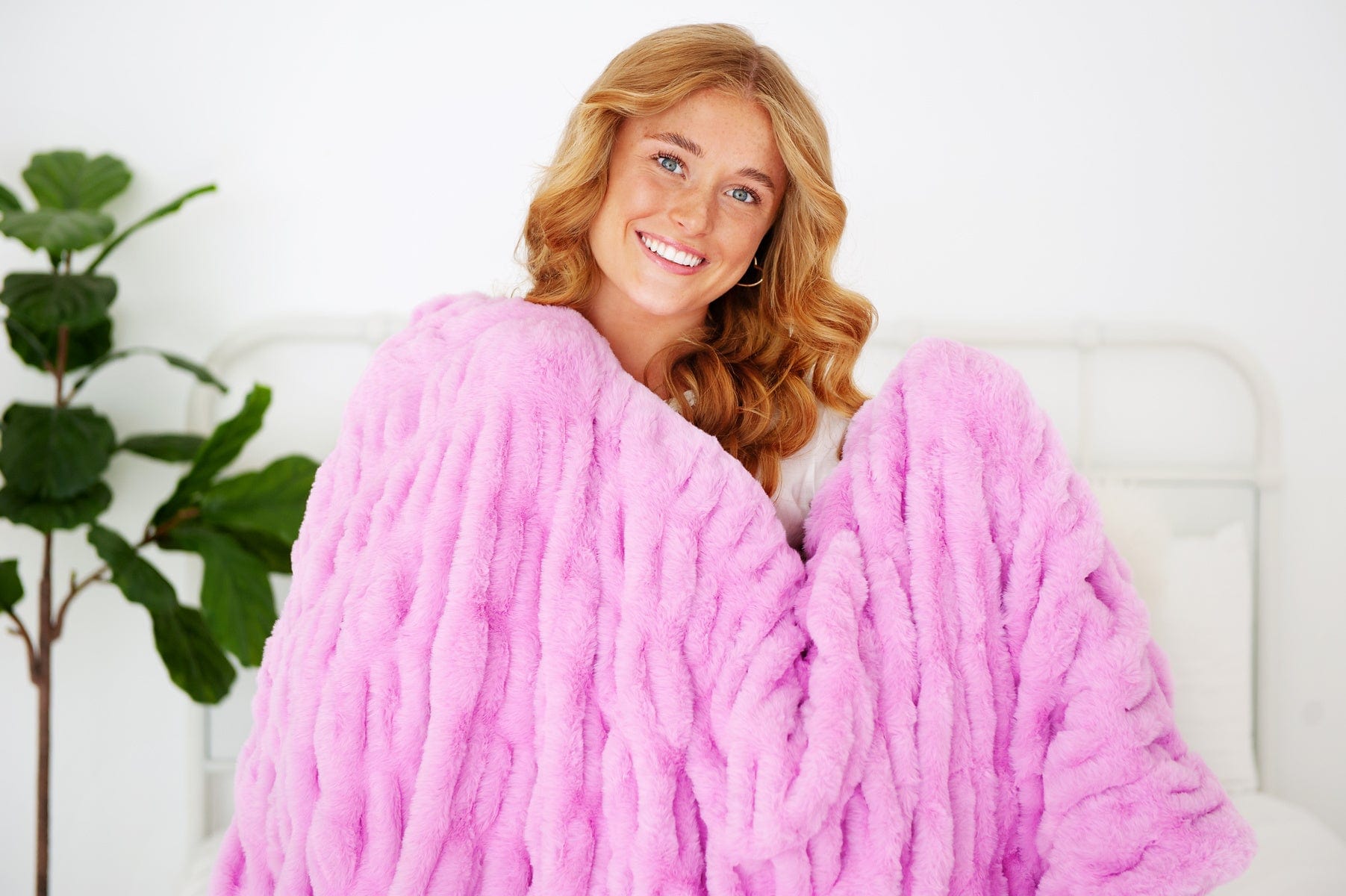 Young woman holding a hot pink ruched blanket. 