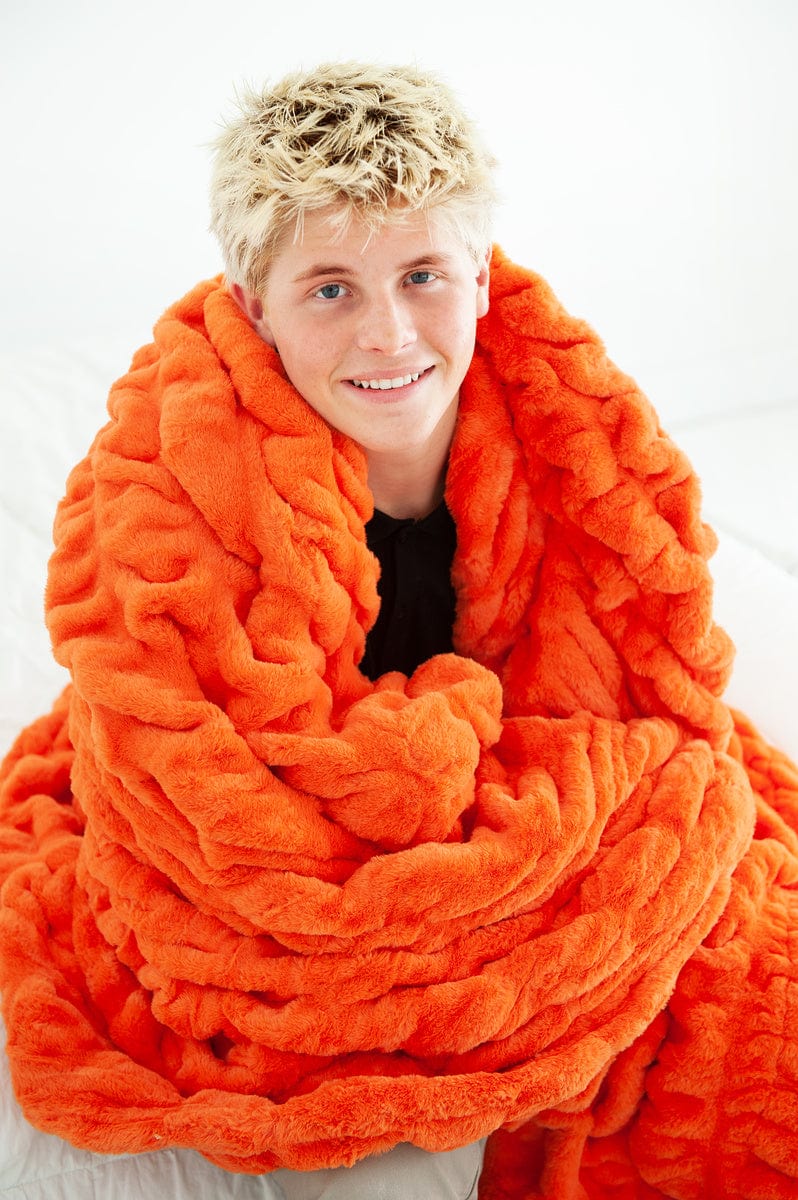 Young man with a vibrant orange blanket around his shoulders. 