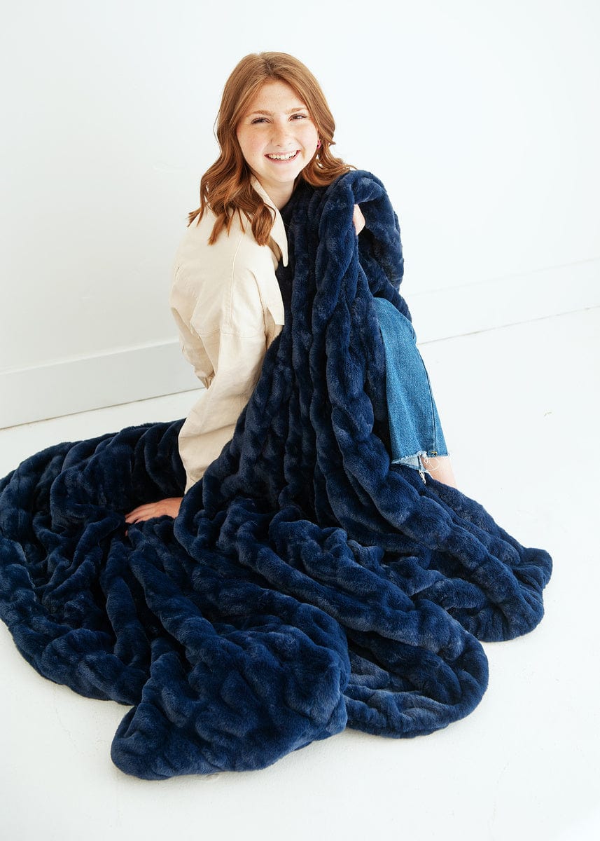 Young woman sitting with a navy blue ruched blanket around her.