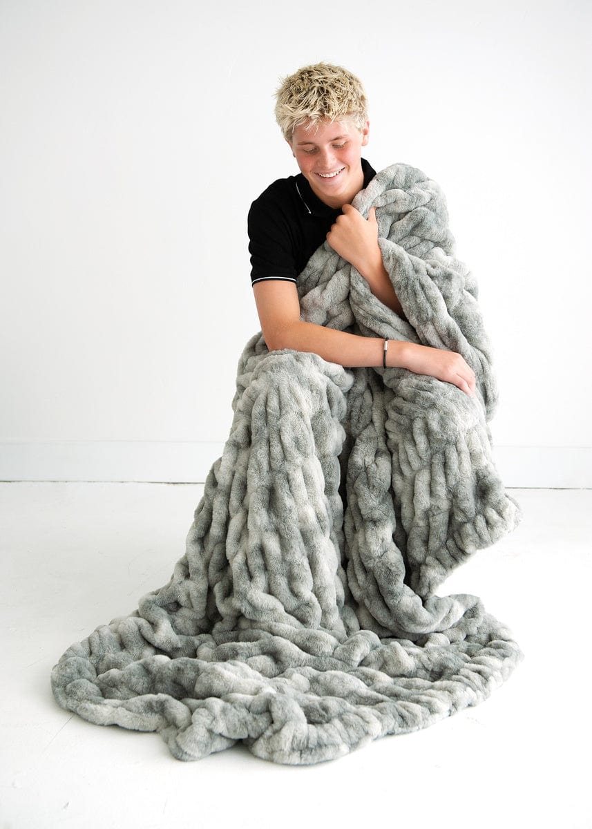 Teen boy sitting wrapped up in a ruched blanket in shades of gray.