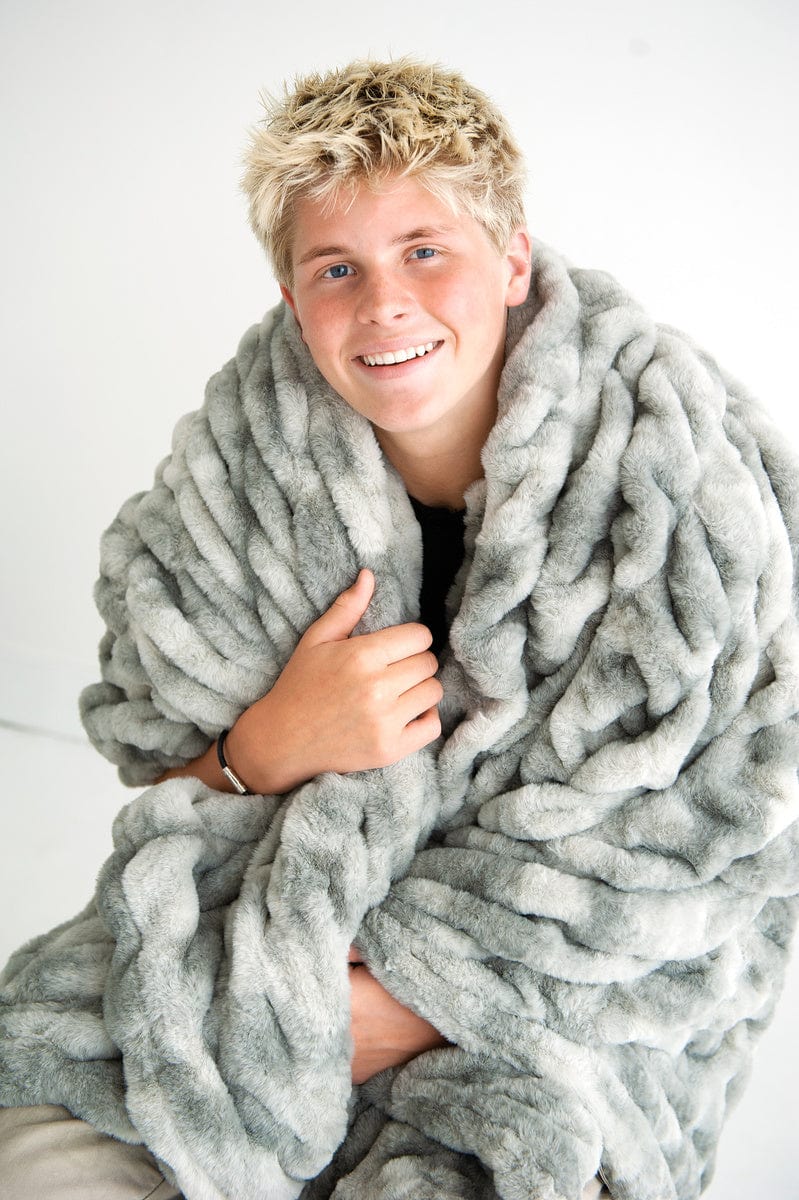 Teenage boy with a variegated gray blanket. 