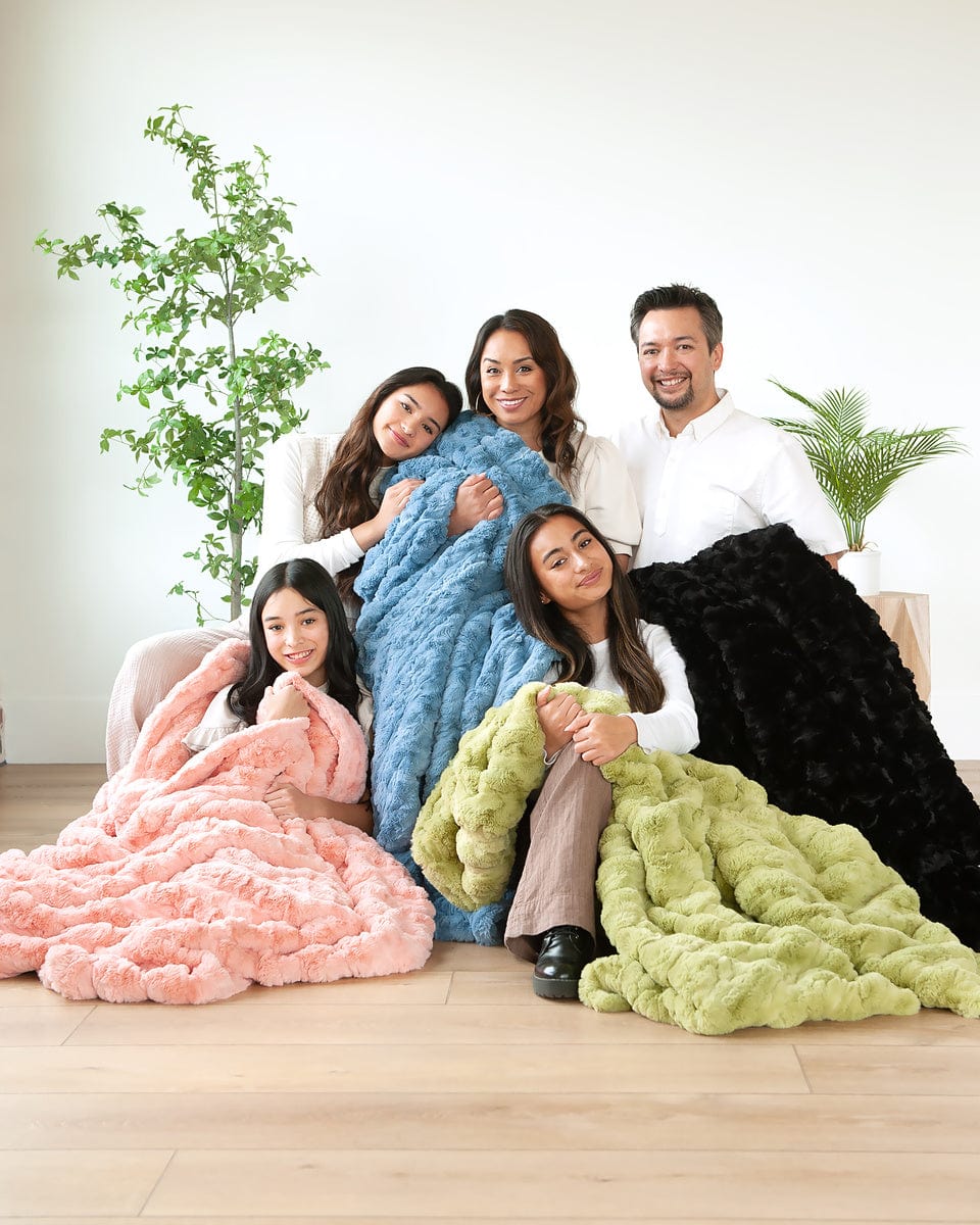 Young family sitting together wrapped up in four different colored blankets.