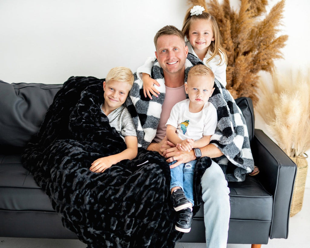 Father sitting with his three children with two plush Minky Couture designer blankets. 