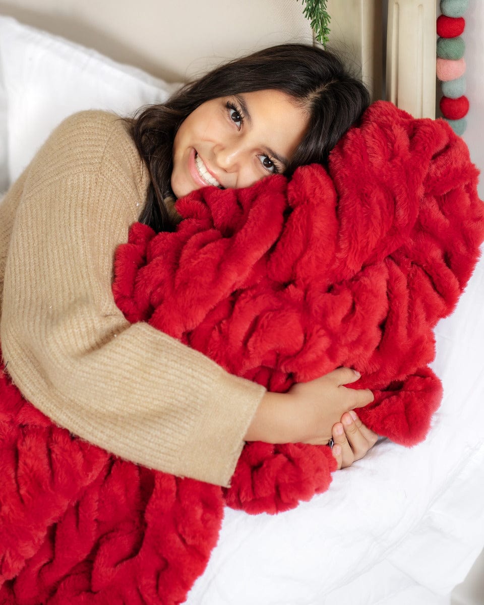 Young woman snuggling up with a red ruched blanket by Minky Couture!