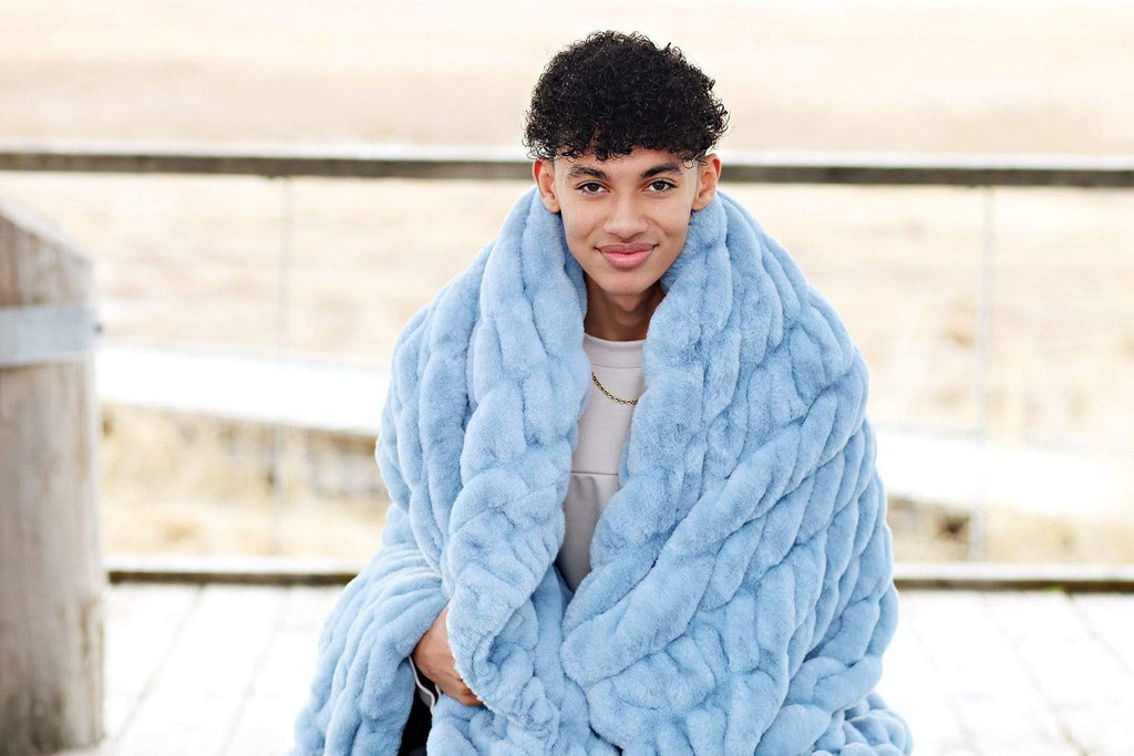 Young man with a powder blue stretchy blanket by Minky Couture wrapped around him.