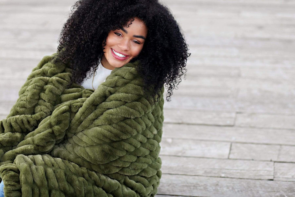 Young woman wrapped up in an army green colored stretchy hugs collection blanket by Minky Couture. 