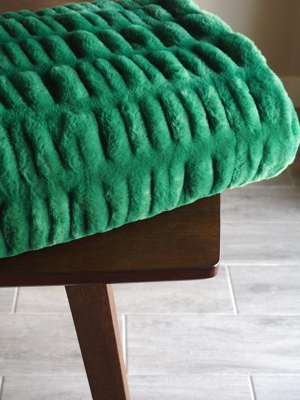 Stretchy green blanket folded neatly on a brown wooden table.