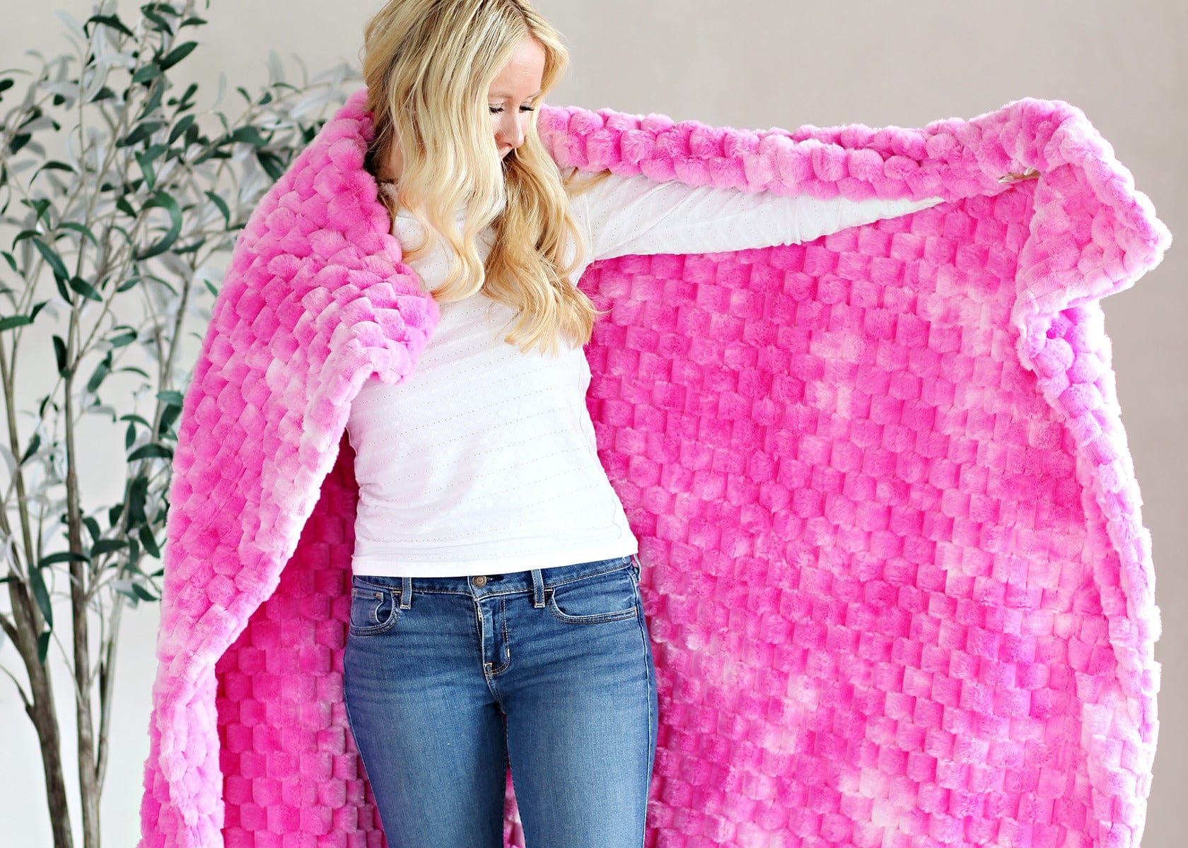 Young women holding up a pink waffle textured blanket.