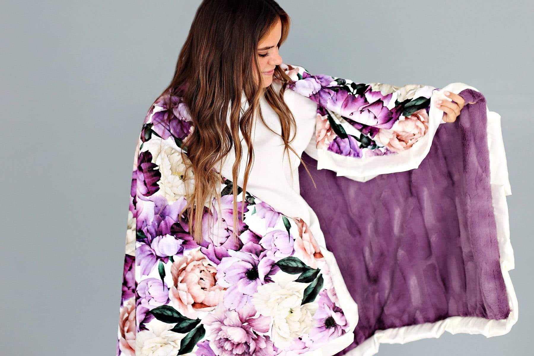 Young woman with the cozy Purple Promise blanket by Minky Couture draped across her shoulders.