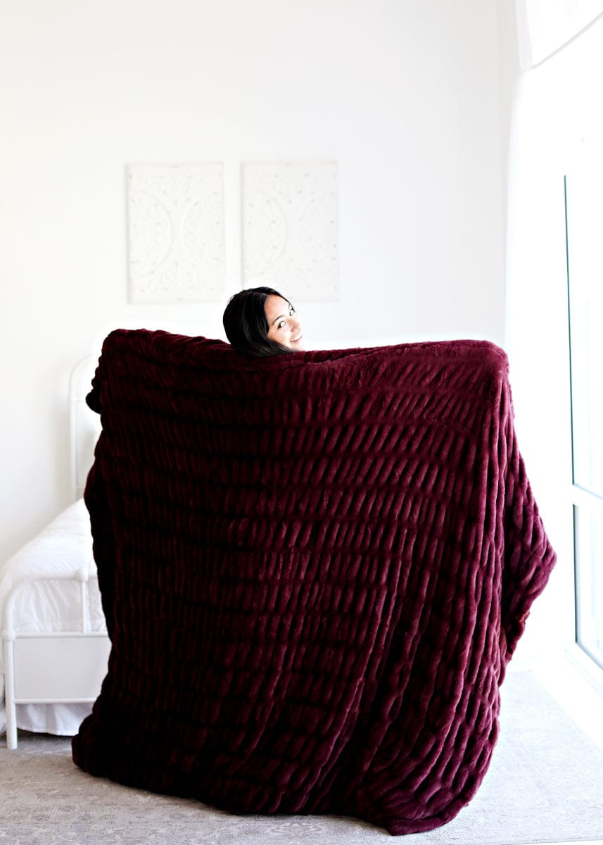 Young women holding up a deep red colored stretchy blanket.