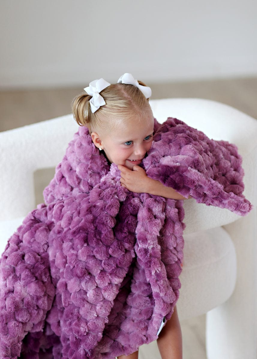 Little girl wrapped in a purple waffle textured blanket.