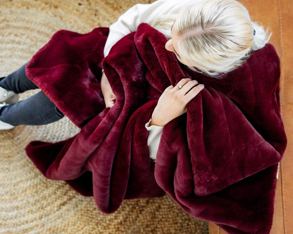 Woman sitting with the Lush Winter Wine blanket by Minky Couture. 