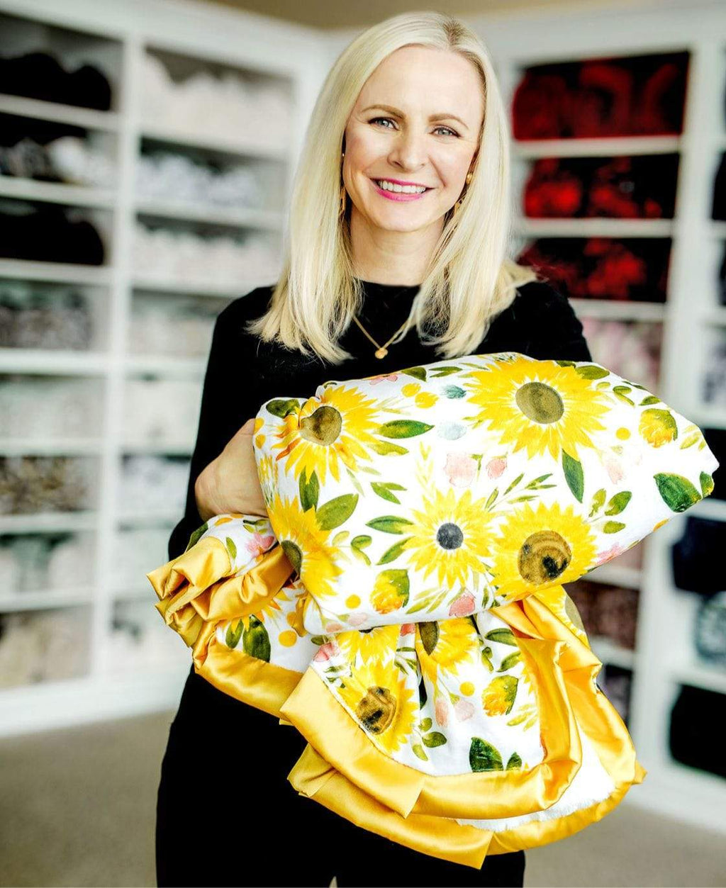 Woman standing holding a yellow watercolor sunflower blanket.
