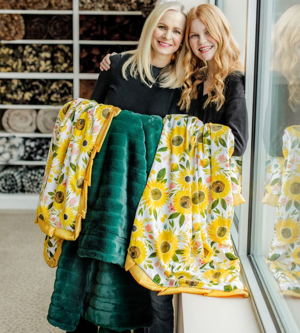 Mother and daughter holding water colored sunflower and emerald minky blankets.