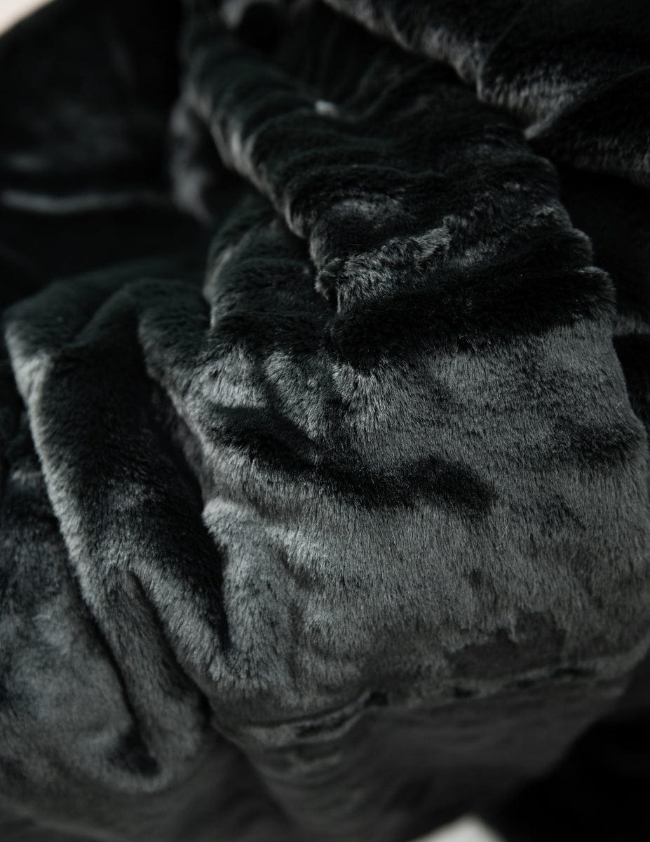 Thick black plush blanket hanging over the back of a couch.