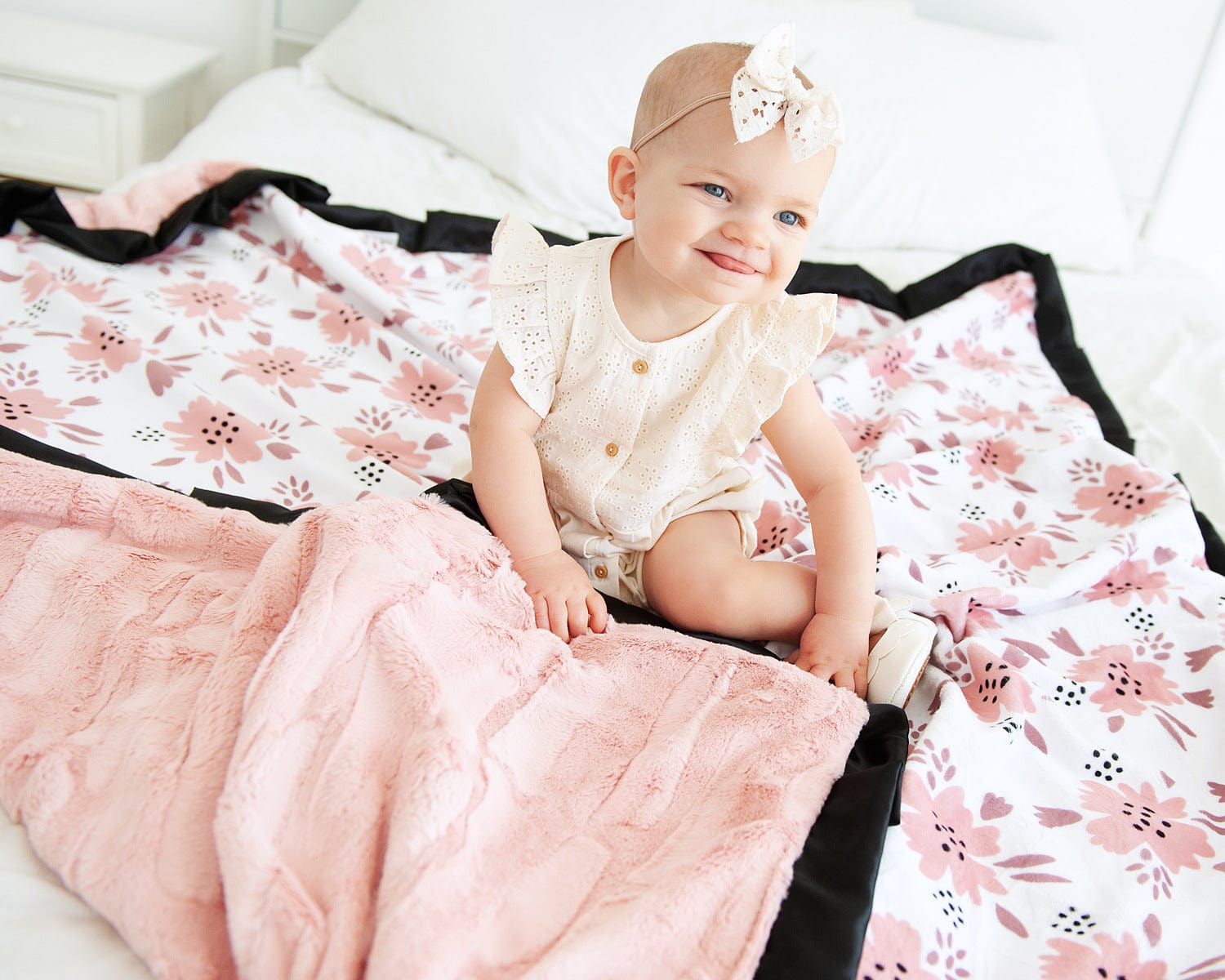Baby girl sitting on top of a pink apricot blossom themed blanket. 