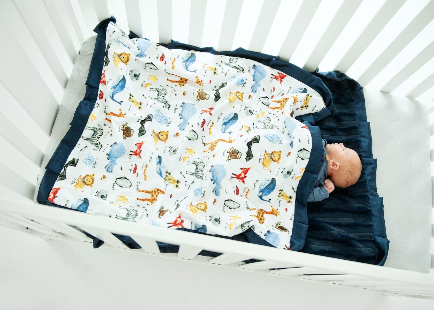 Zoo animal blanket over an infant in a crib. 