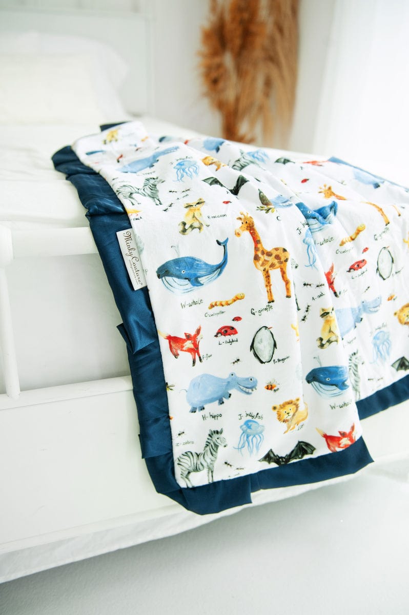 Zoo animal themed blanket draped over the end of a bed. 