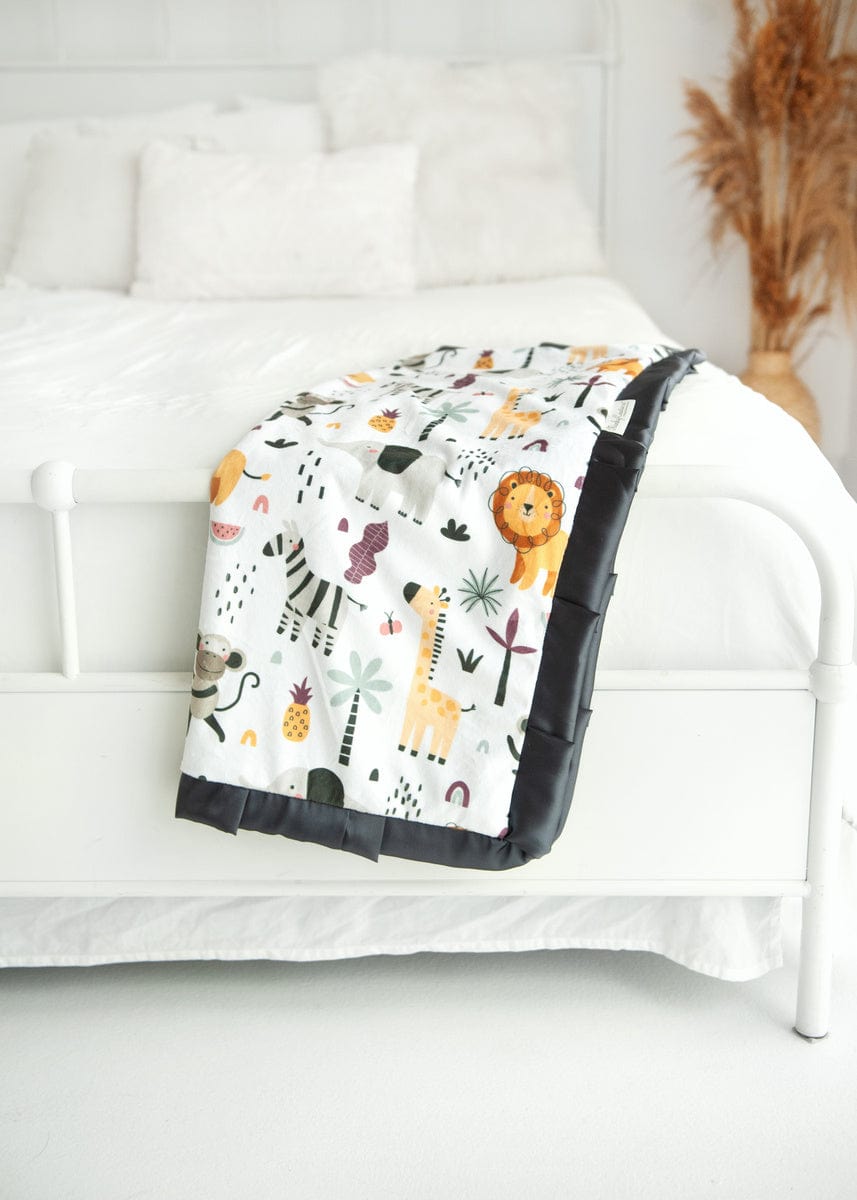 Cartoon zoo animal themed blanket laying off the end of a bed. 