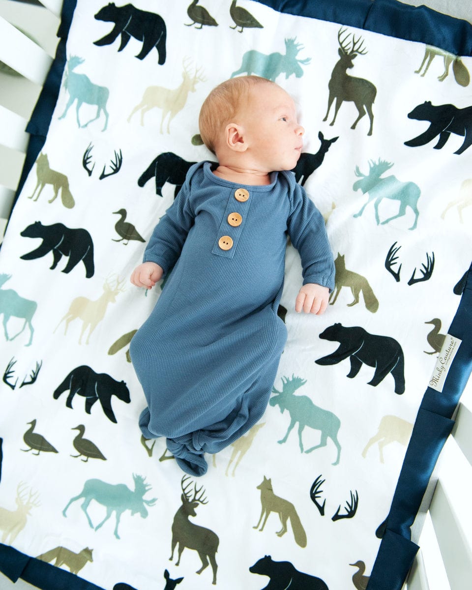Baby boy laying on Teton woodland animal themed blanket with blue, green and gray animals.