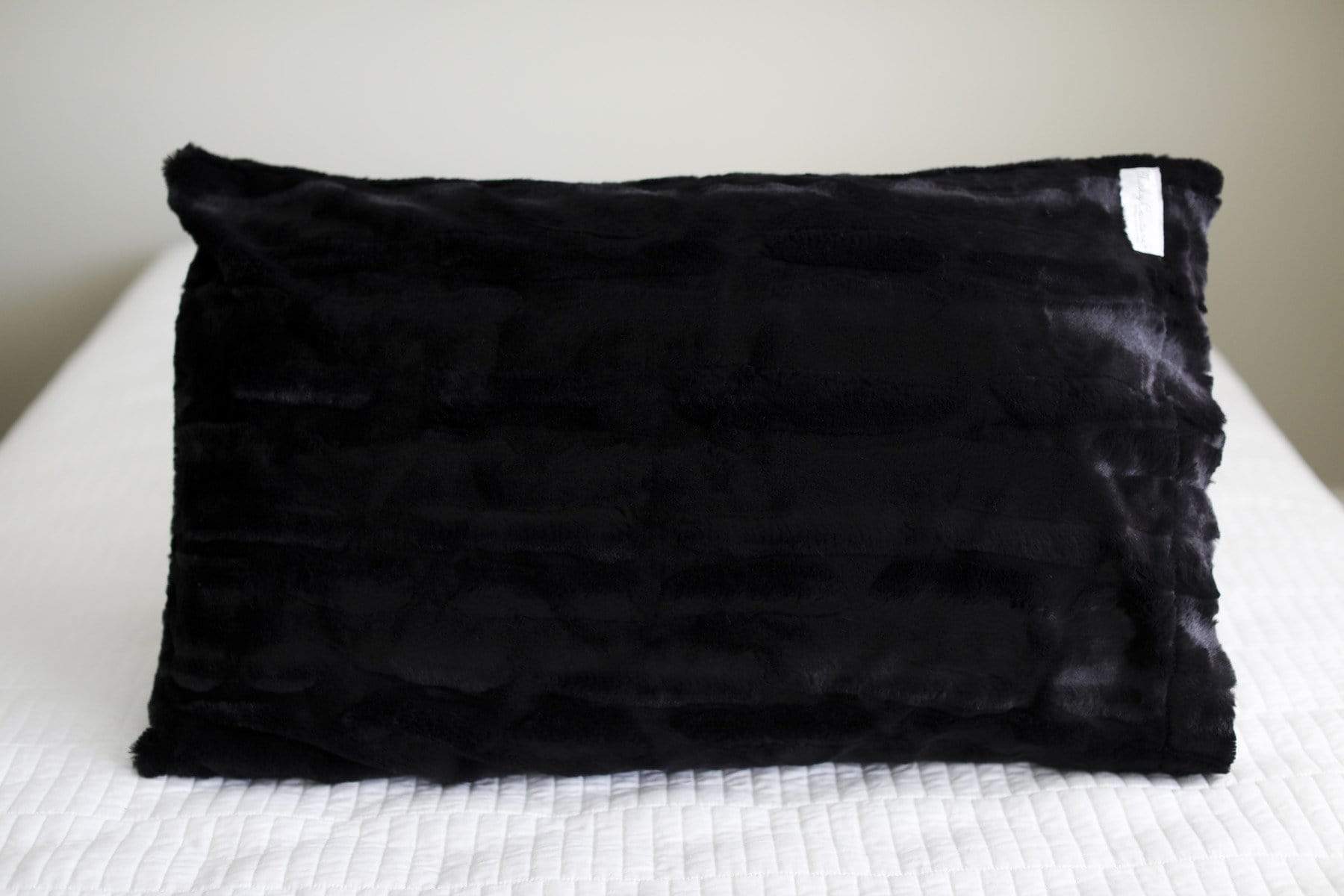 Black plush pillowcase by Minky Couture sitting on a bed. 