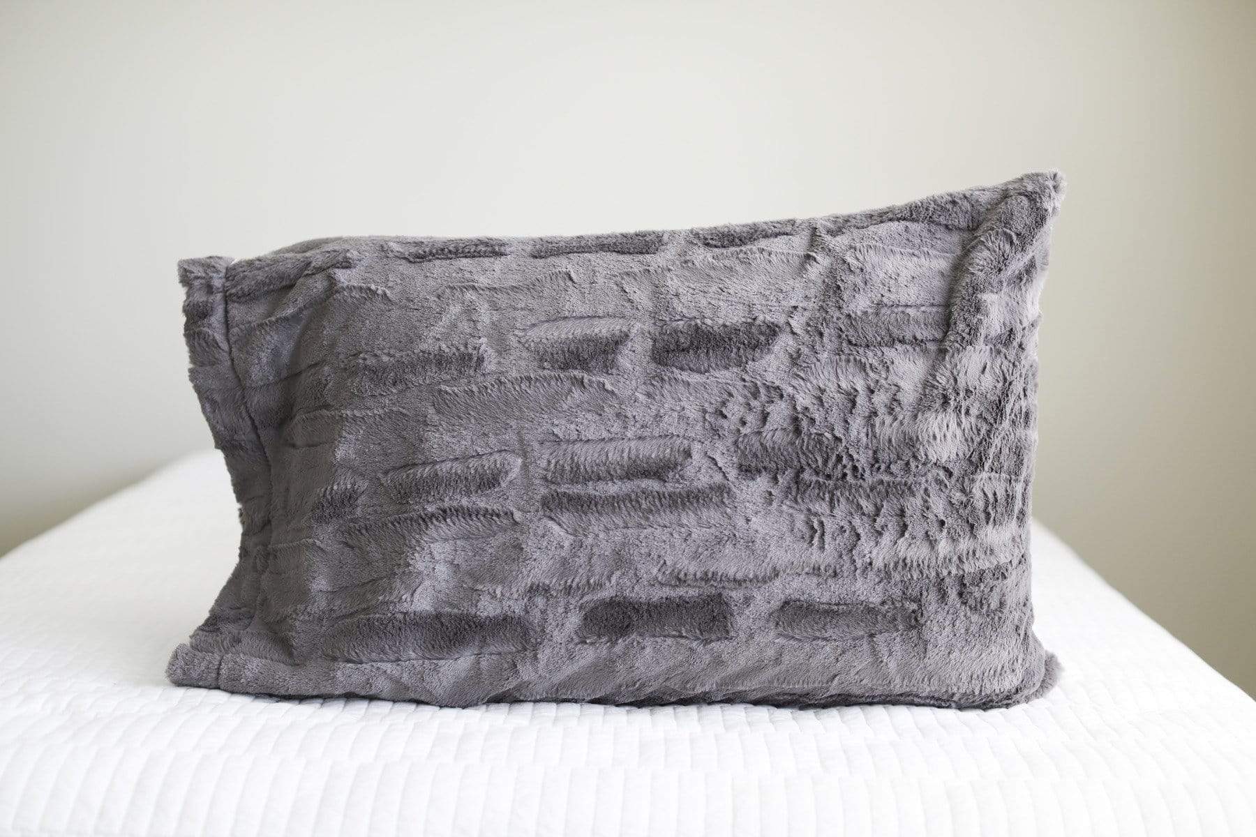 Charcoal gray plush Minky Couture pillowcase sitting on a bed. 