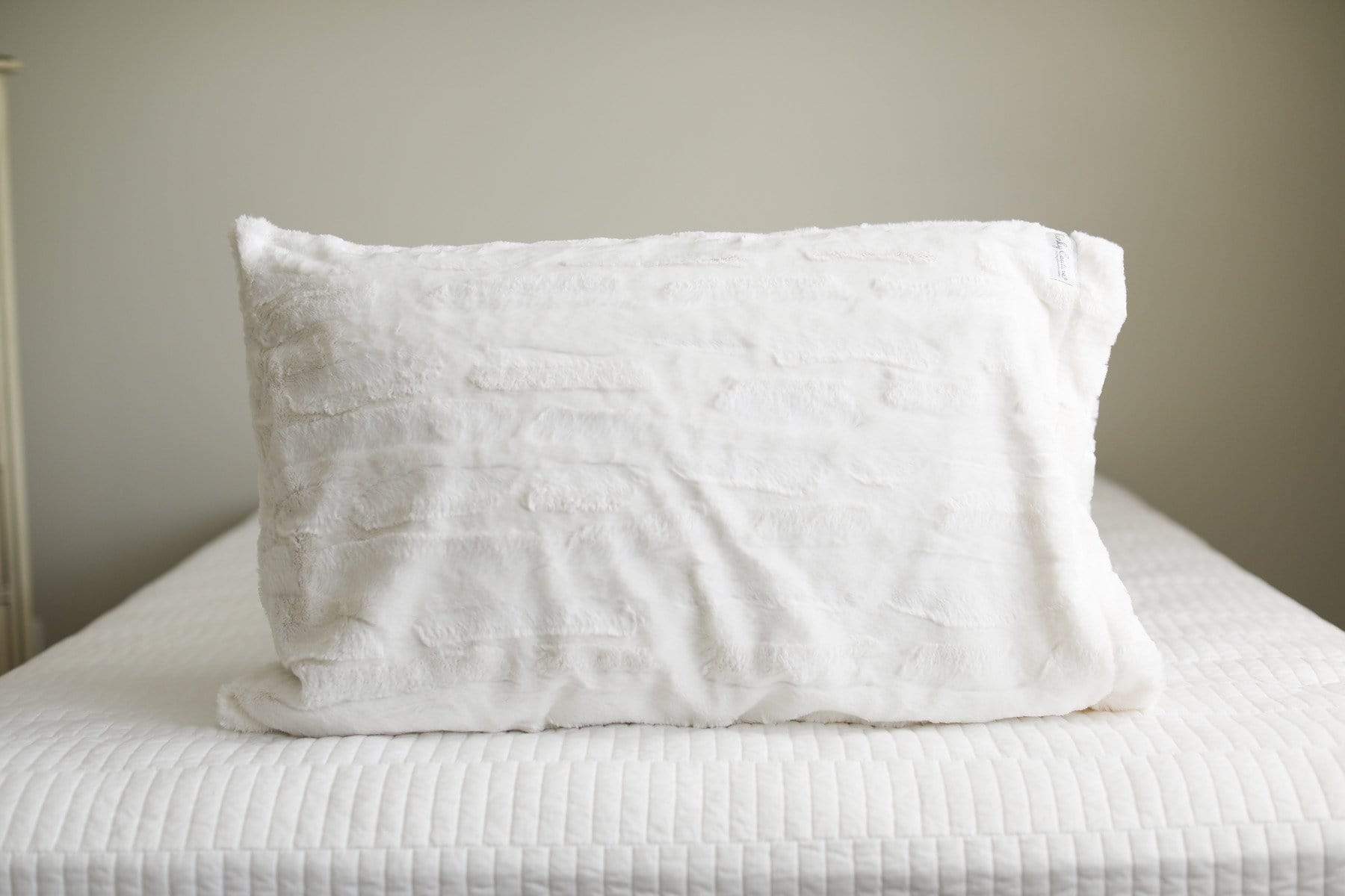 Creamy white Minky Couture plush pillowcase sitting on a bed. 