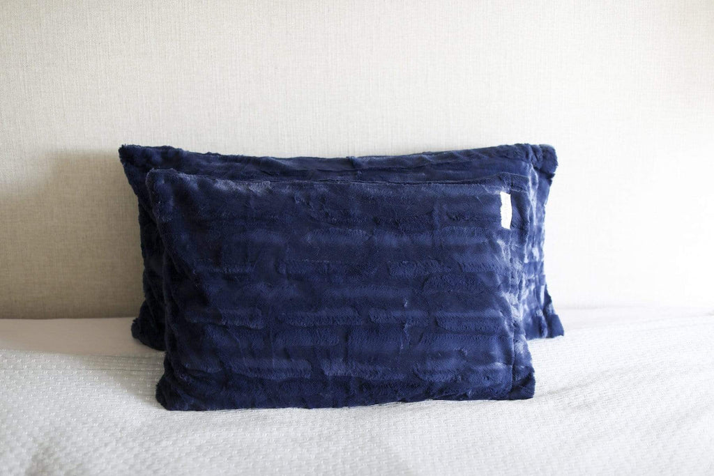 Two plush navy pillows by Minky Couture on a bed. 