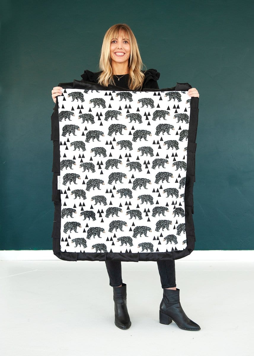 Woman standing holding a small bear patterned blanket.