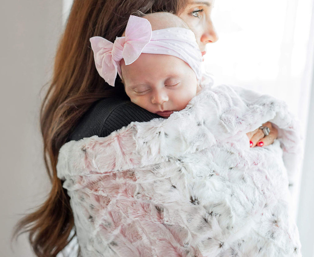 Mother holding her infant daughter wrapped in the Sandra Pink blanket by Minky Couture.