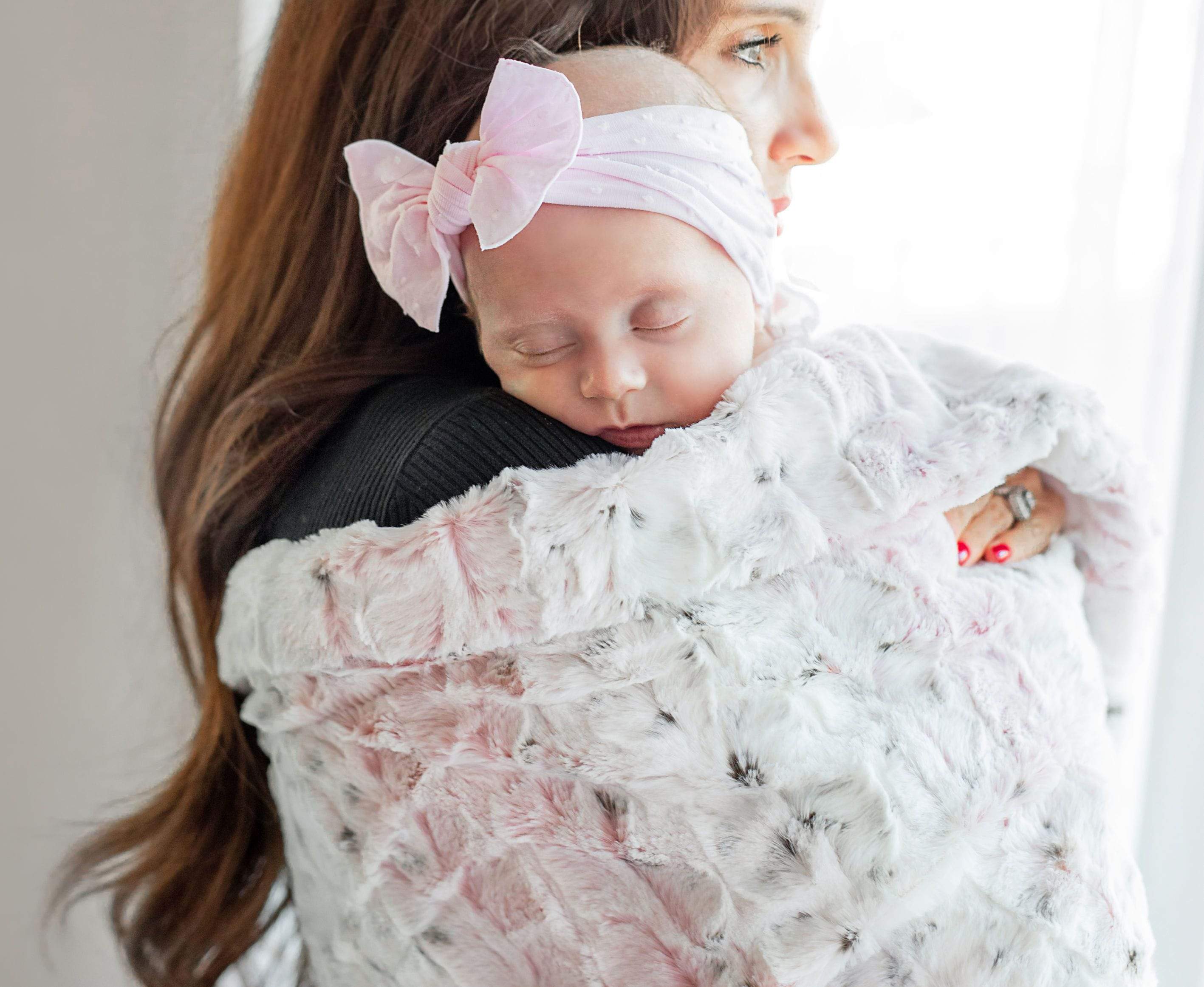Mother holding her infant daughter wrapped in the Sandra Pink blanket by Minky Couture.