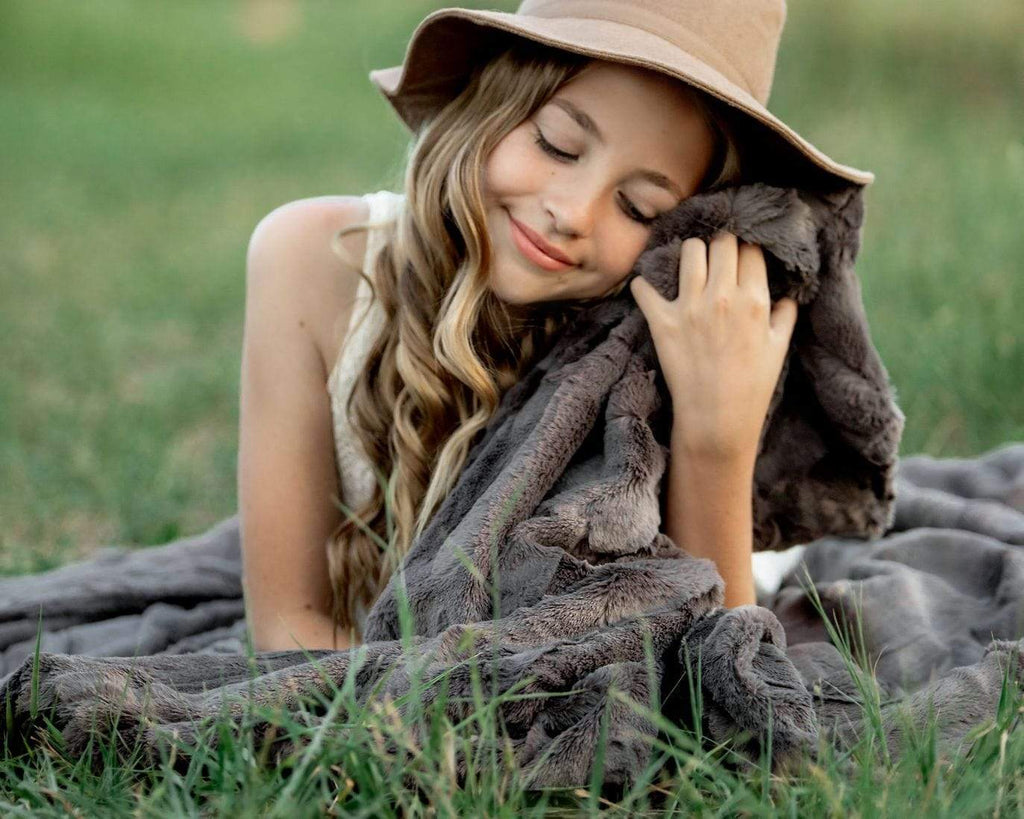 Girl sitting with her sorbet charcoal blanket by Minky Couture. 