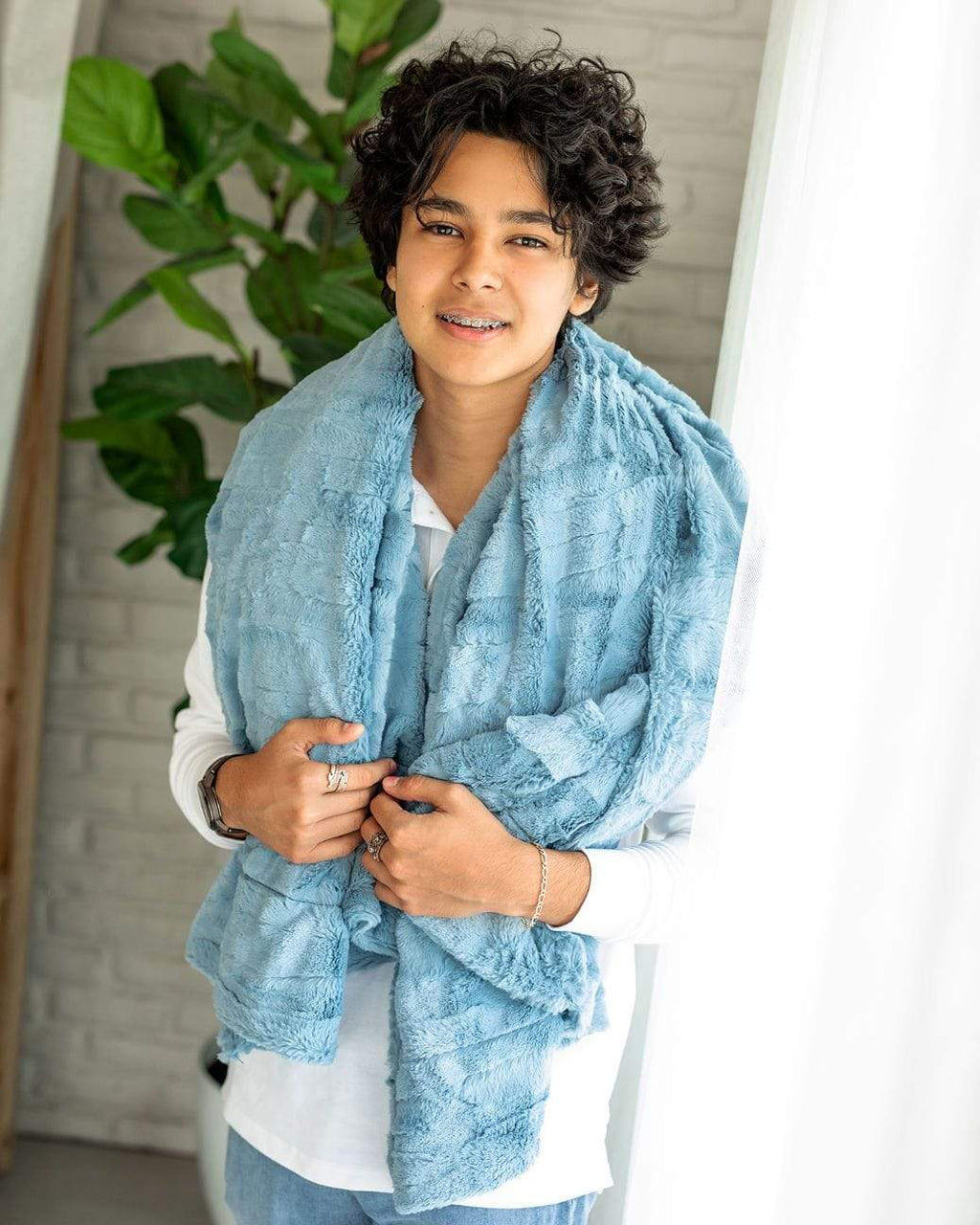 Teenage boy standing with the sorbet denim blanket by Minky Couture laid across his shoulders. 