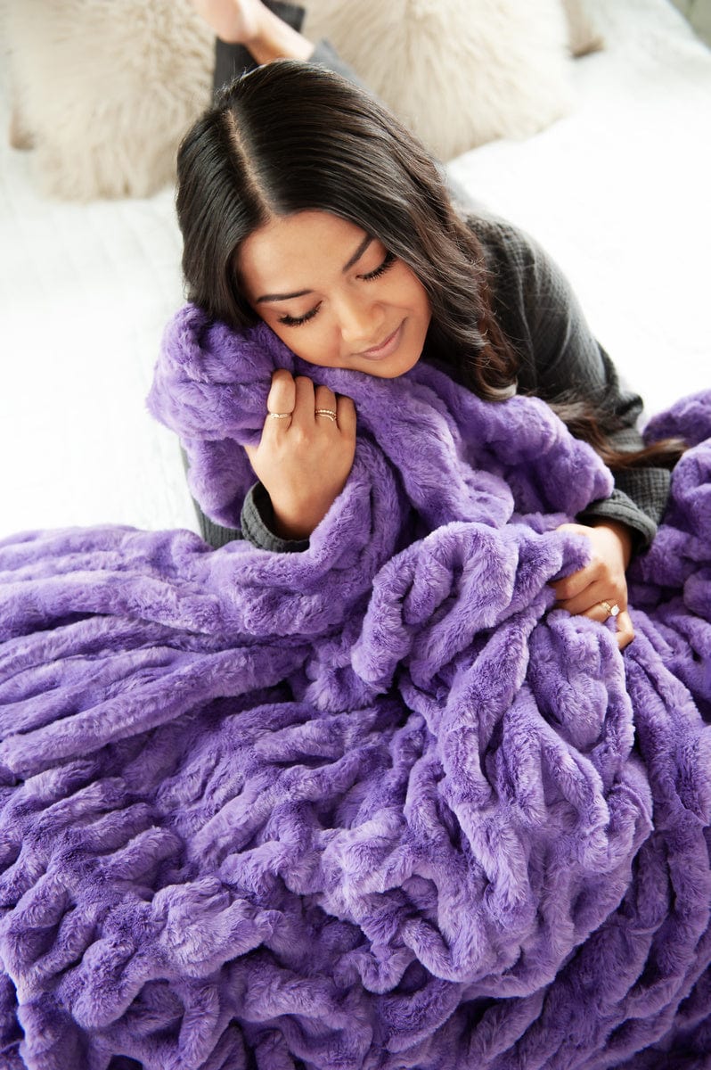 Woman holding a vibrant purple ruched blanket.