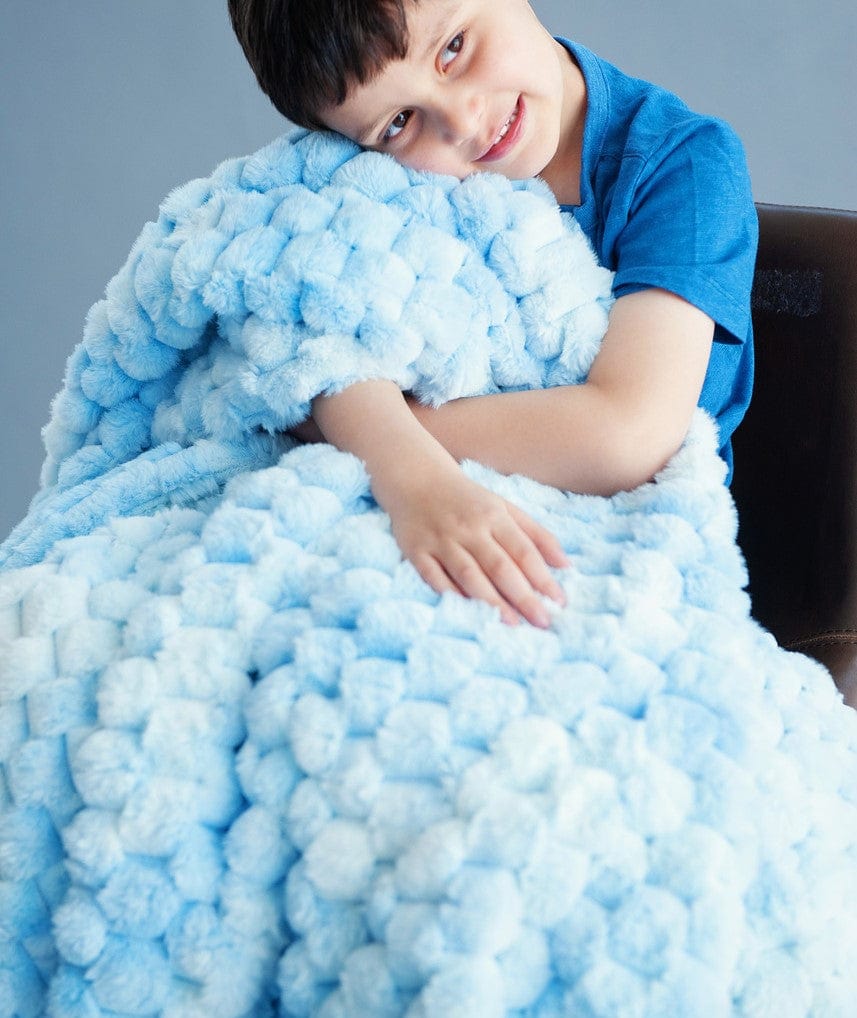 Little boy hugging a light blue waffle patterned blanket. 