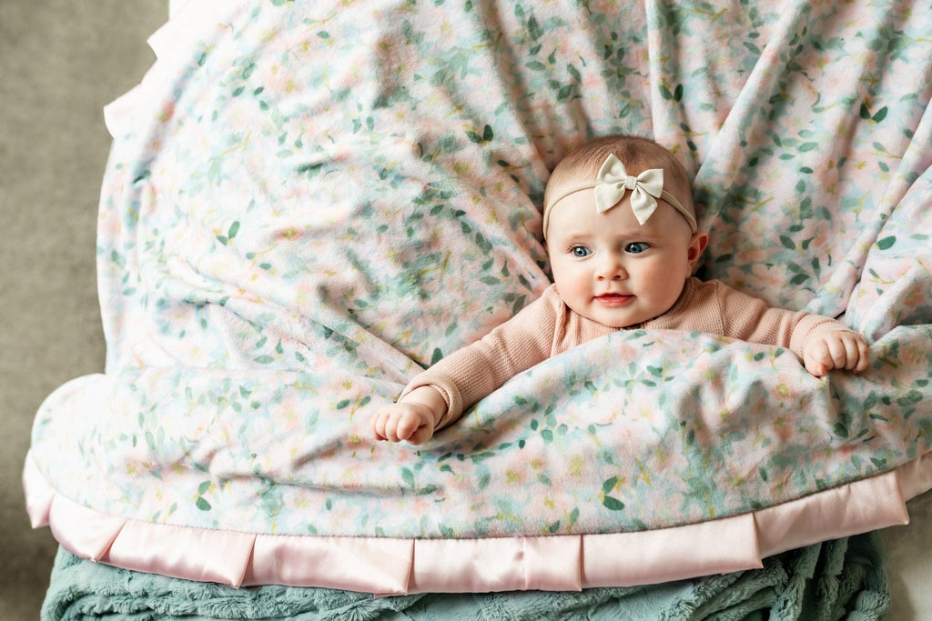 Baby girl wrapped up in a blush and blue floral patterned Minky Couture blanket.