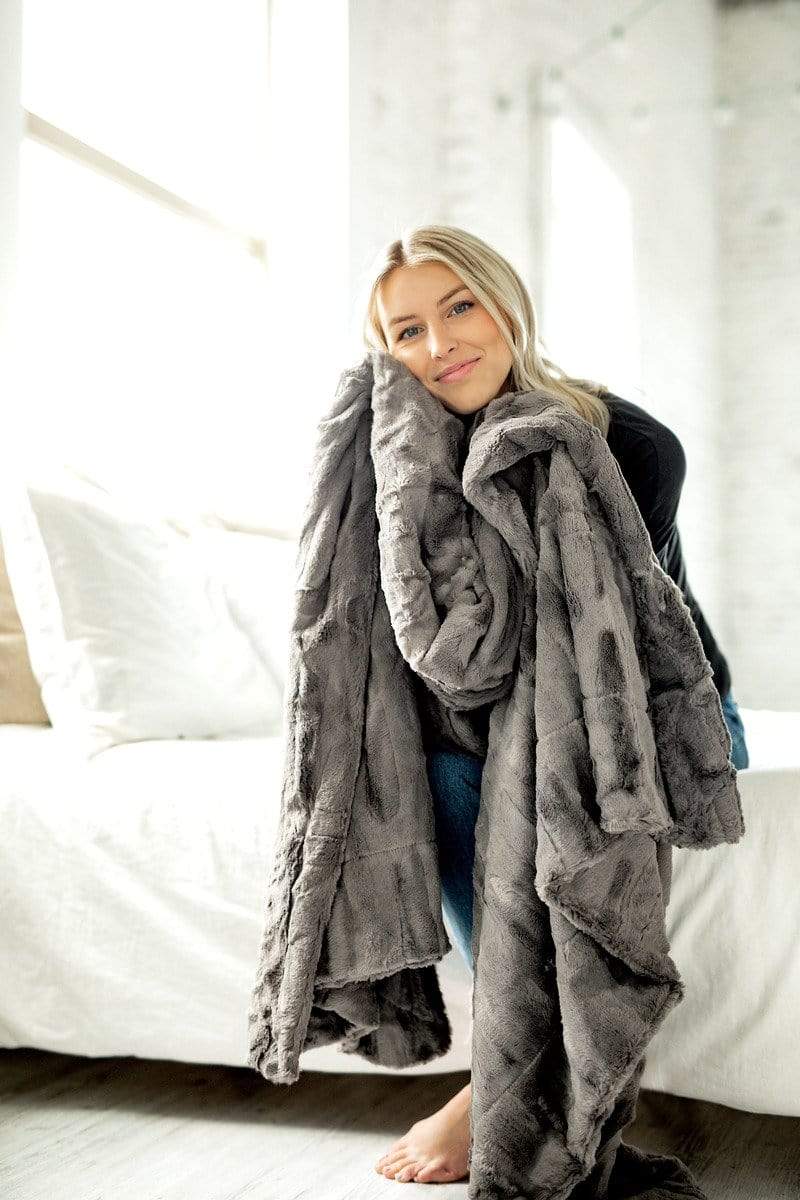 Young woman snuggled up with the cozy sorbet charcoal blanket by Minky Couture. 
