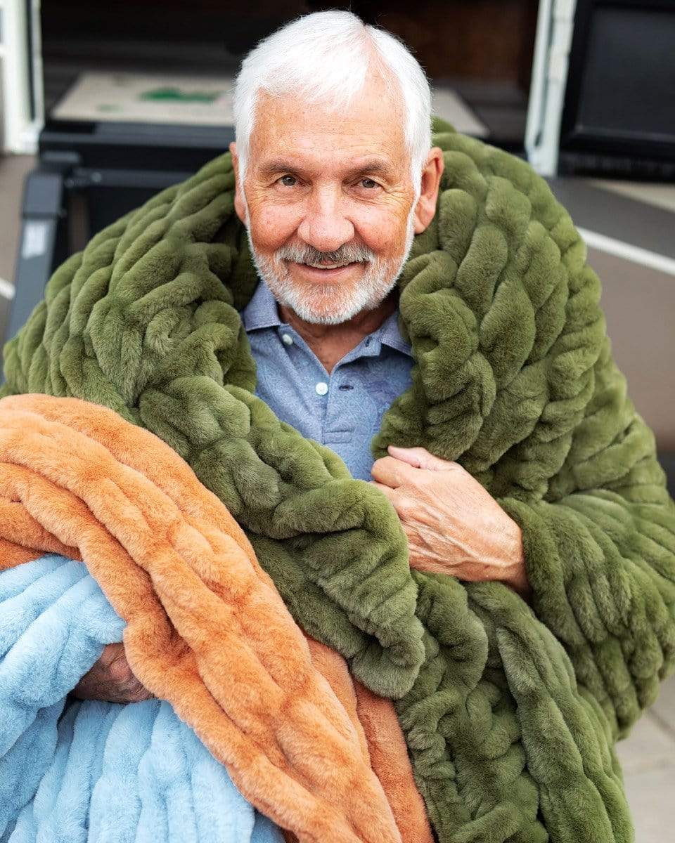 Older gentleman sitting on steps with three stretchy Minky Couture blanket. 
