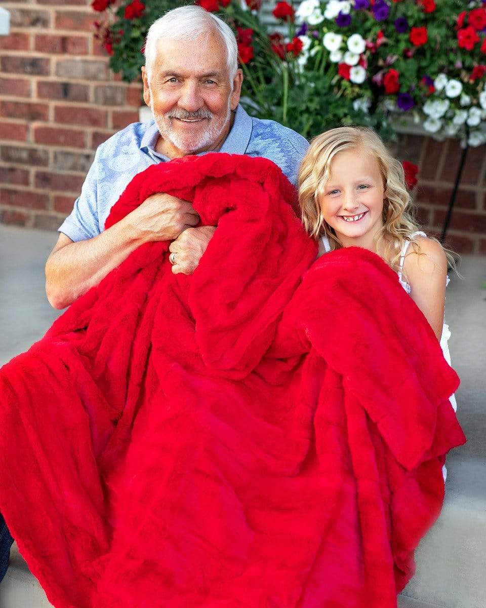 Grandfather sitting on porch steps under a thin red Minky Couture blankets with his grand daughter.
