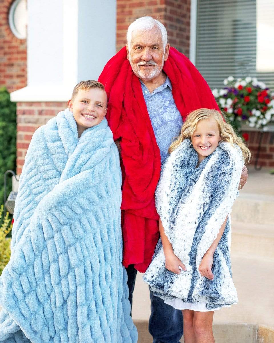 Grandfather standing on porch steps with two grandchildren holding blue and red Minky Couture blankets. 