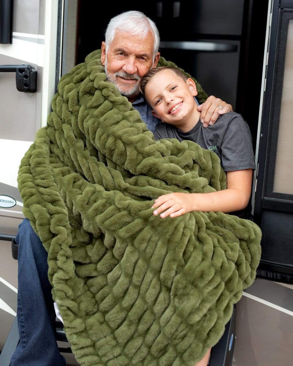 Grandfather and grandson sitting in a camper wrapped up in a camp green stretchy Minky Couture blanket. 