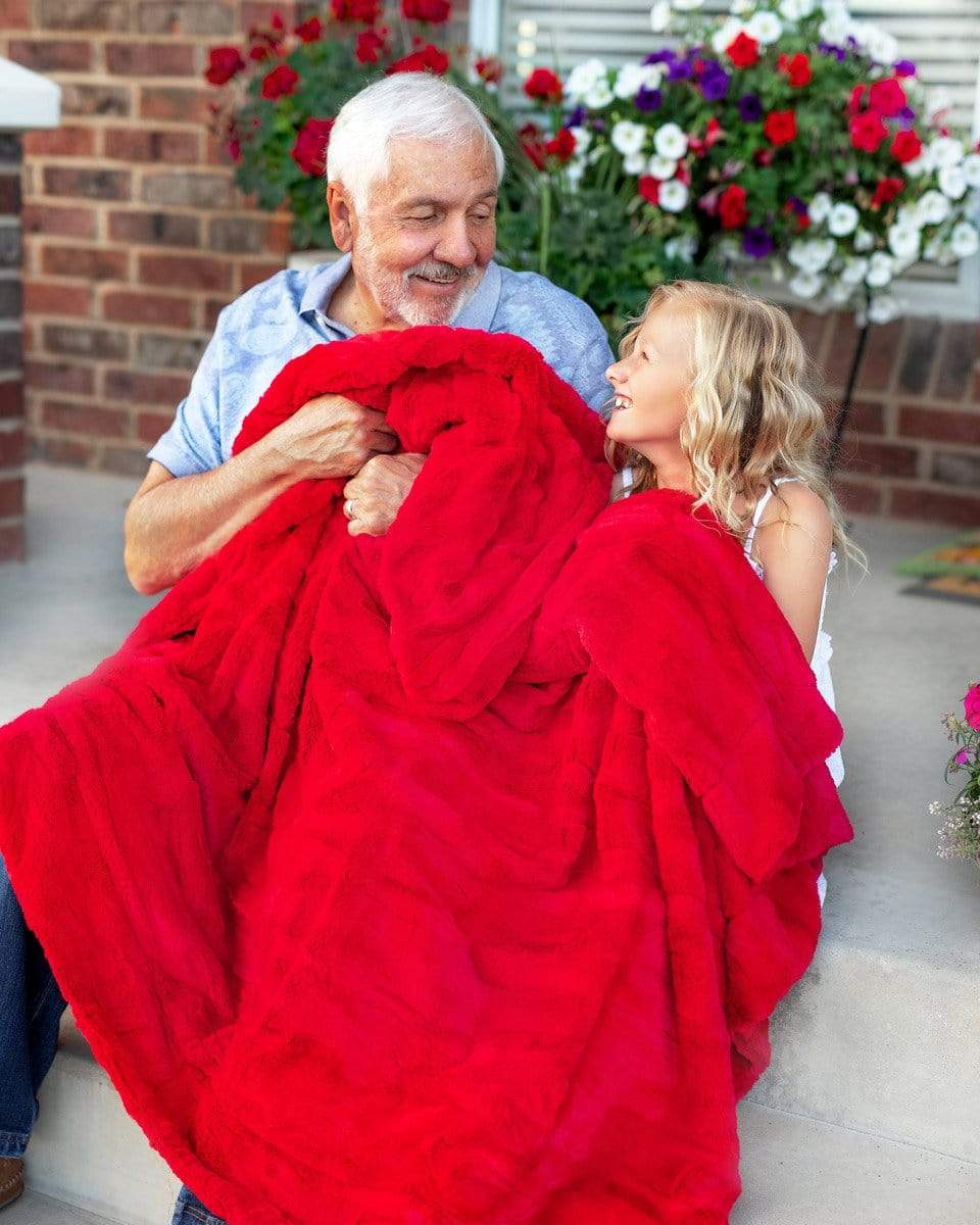 Grandfather sitting on porch steps under a thin red Minky Couture blankets with his grand daughter.