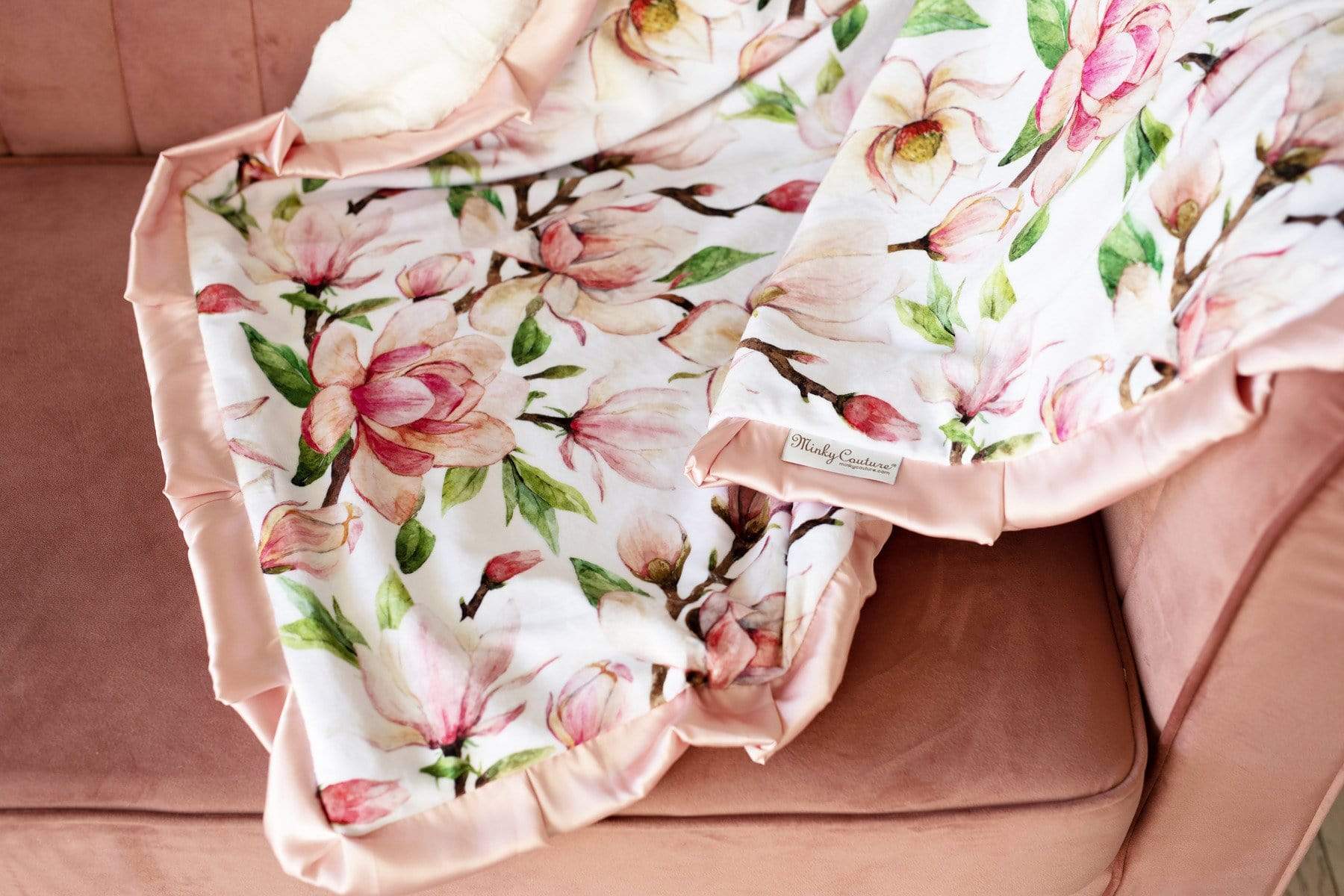 Pink Aspirations blanket by Minky Couture laid across a couch to show pattern and texture. 