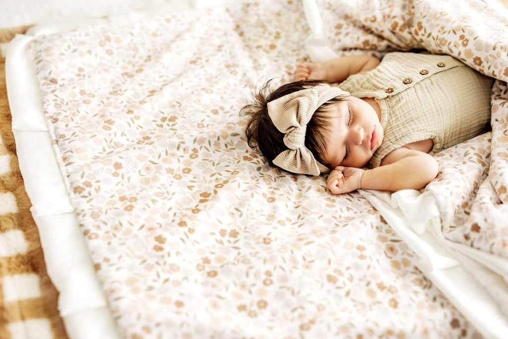 Baby girl laying wrapped up in a floral print blanket.